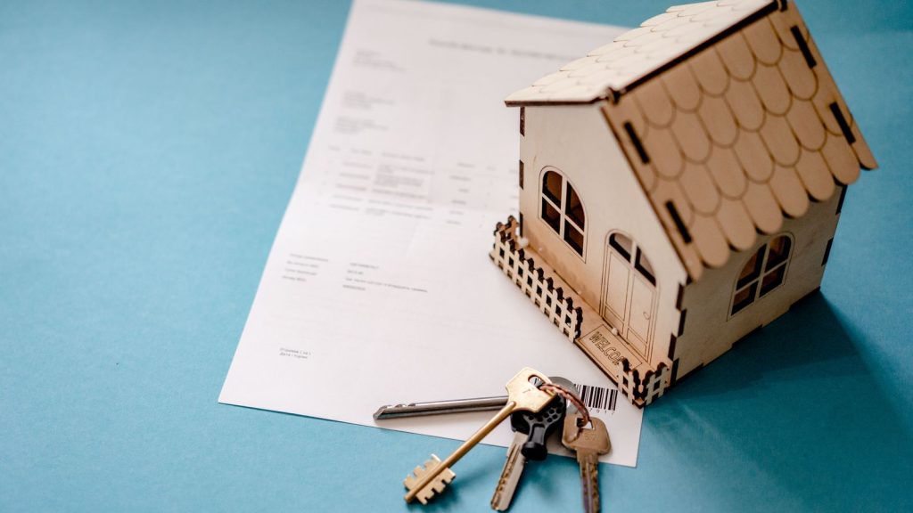 House keys and a signed property contract beside a model house, illustrating stamp duty payable when buying a home
