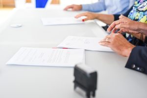 Two people signing a property contract at a table during the conveyancing process