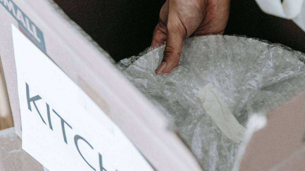 Household items being packed into a labelled cardboard moving box